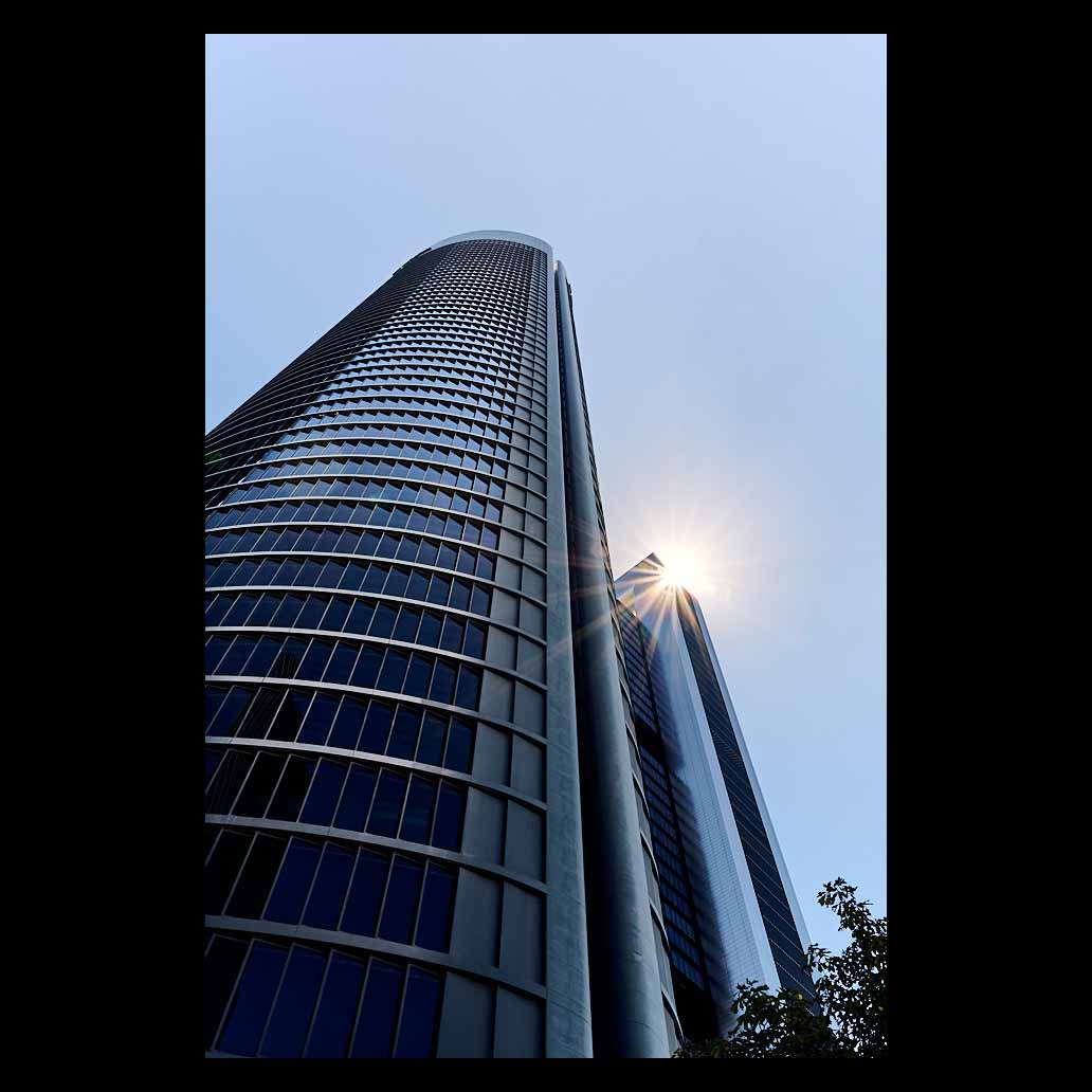 contrapicado de la torre PWC muestra el relieve de sus vidrieras y una Sun Stars ilumina la escena