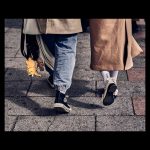 Escena de calle de los pies de una pareja andando con un calzado llamativo donde dice "Fashion"