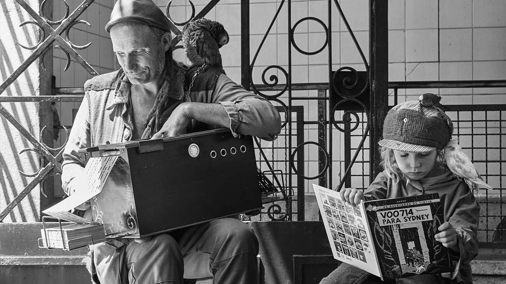 Padre e hija se exponen en la calle toocando el organillo mientras la hija lee un cuento de Tintín