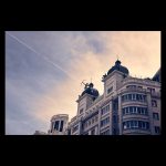 Diana Cazadora sobre un edificio de la Gran Vía de Madrid cuando una estela de avión se cruz con su arco