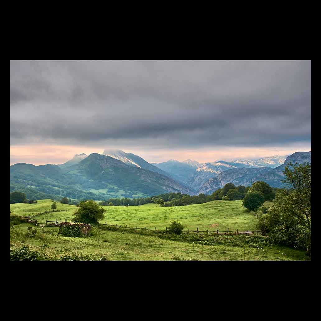 Precioso valle verde en Asturias en un día nublado donde la luz de cuela para iluminar las montañas del fondo