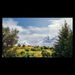 Paisaje de un verde campo, cielo azul y grandes nubes blancas